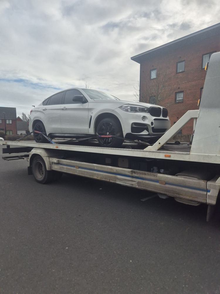 White SUV loaded on a flatbed recovery truck